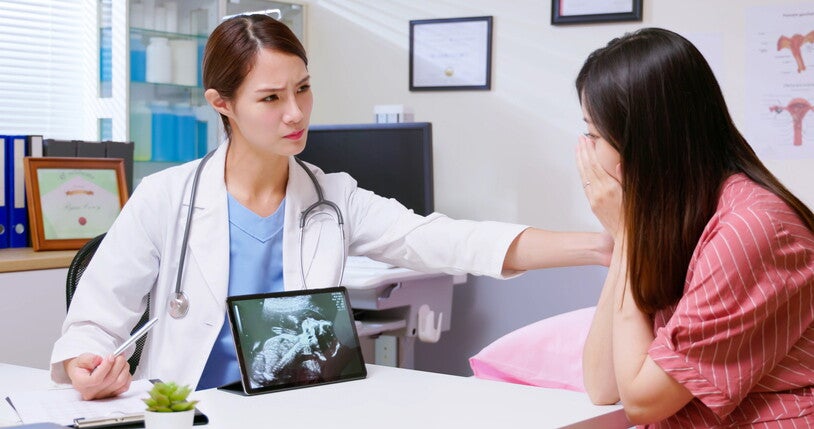 ผู้หญิงปรึกษาคุณหมอพร้อมดูภาพอัลตราซาวด์ในครรภ์