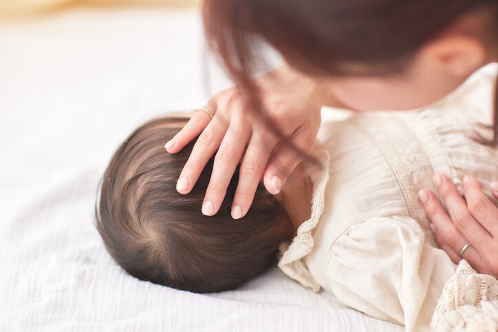 มือแม่จับหัวลูกที่มีขวัญบนหัว