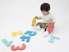 เด็กชายนั่งเล่นแผ่นโฟมรูปตัวเลขสีสันสดใส