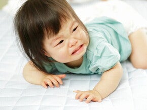 เด็กผู้หญิงท้องผูกกำลังร้องไห้ ขณะนอนคว่ำ