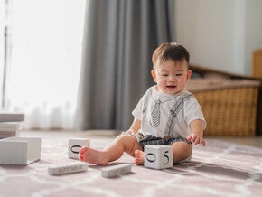 เด็กกำลังเล่นบล็อคไม้ตัวเลขบนพรมในห้องนั่งเล่น