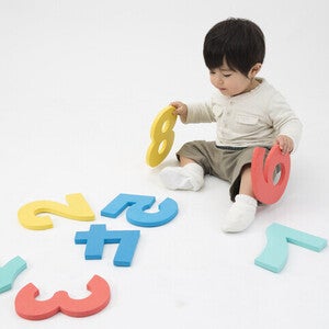 เด็กชายนั่งเล่นแผ่นโฟมรูปตัวเลขสีสันสดใส