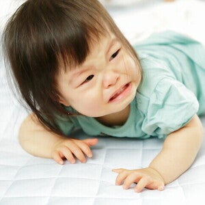 เด็กผู้หญิงท้องผูกกำลังร้องไห้ ขณะนอนคว่ำ