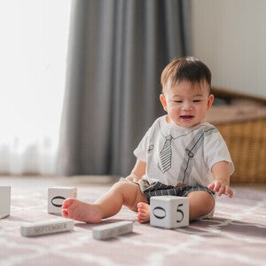 เด็กกำลังเล่นบล็อคไม้ตัวเลขบนพรมในห้องนั่งเล่น