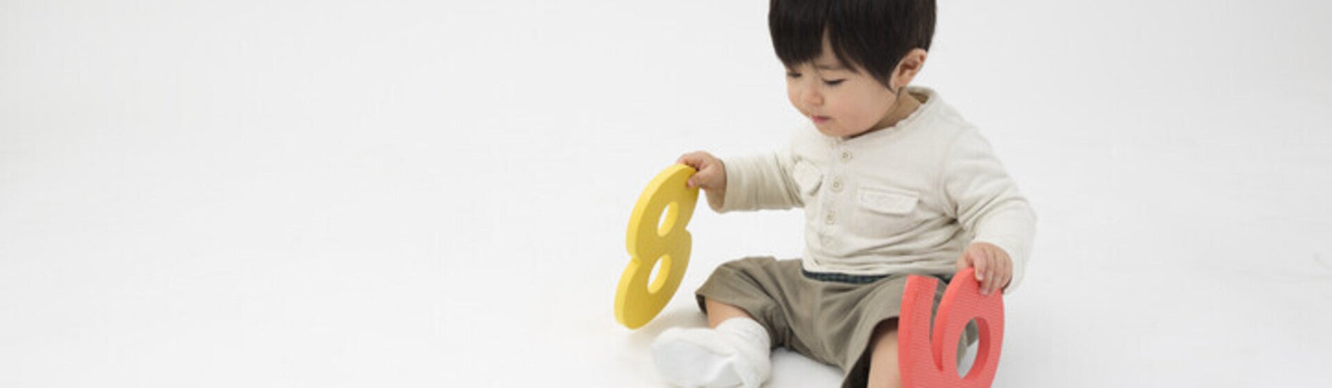 เด็กชายนั่งเล่นแผ่นโฟมรูปตัวเลขสีสันสดใส