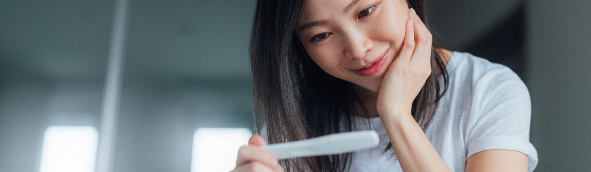 ผู้หญิงทำท่าเท้าคางและกำลังมองผลจากที่ตรวจครรภ์